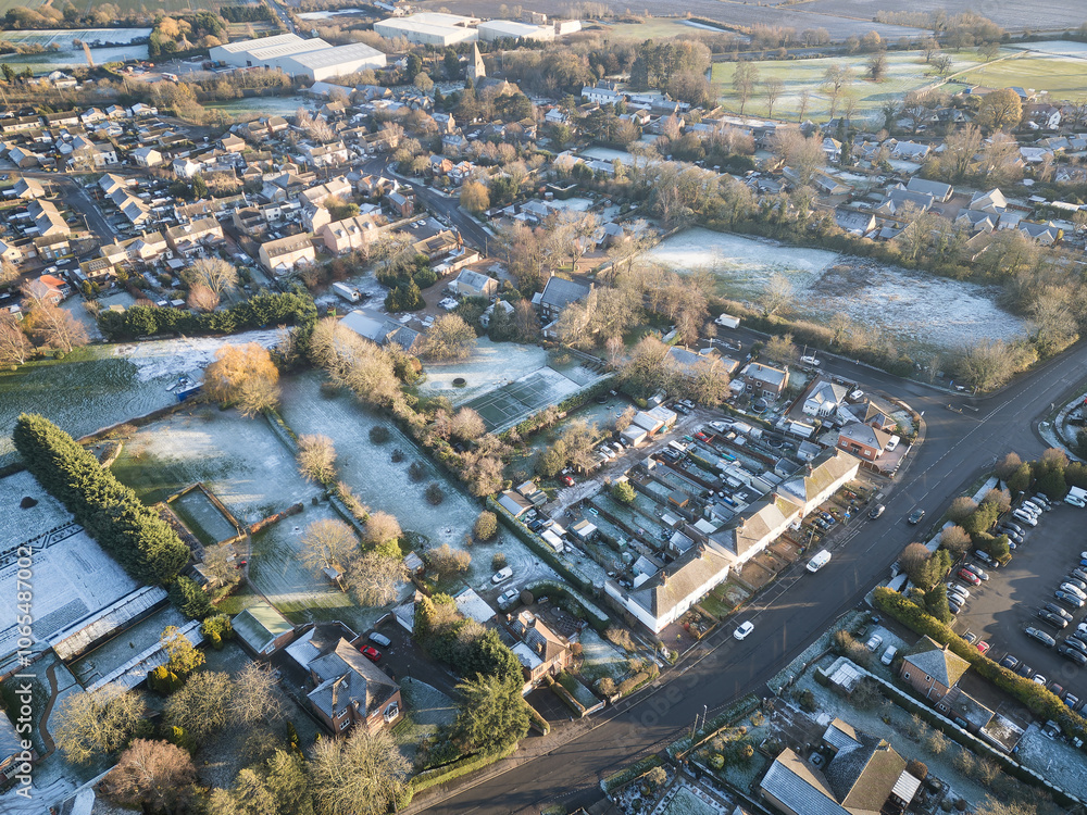 Fototapeta premium Aerial view of old and new houses seen on a frosty morning in Cambridgeshire, UK. Large, snow covered gardens are visible.