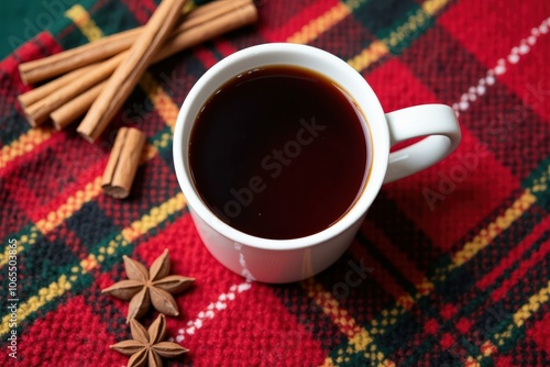 Warm and Cozy Holiday Coffee Mug with Cinnamon Sticks and Star Anise on a Red Plaid Blanket photo