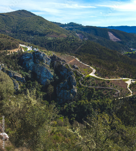 sweeping view of rolling hills covered with dense forest and rugged rocky outcrops, adorned with a winding wooden walkway