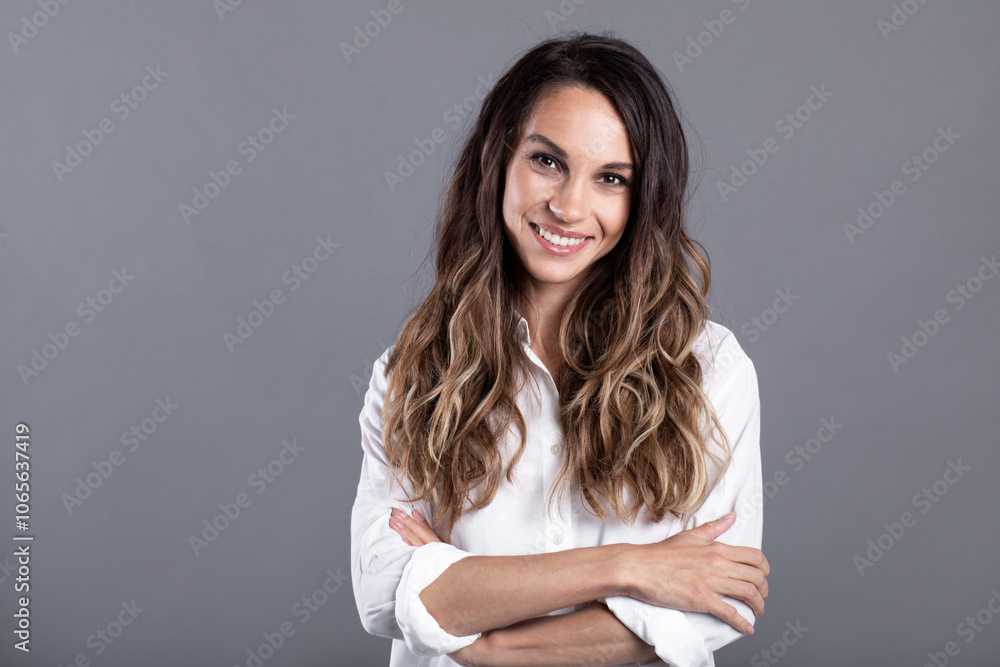 Smiling brunette businesswoman crossed arms against gray background. Confident female professional is wearing white shirt Smiling brunette businesswoman crossed arms against gray background. Confident female professional is wearing white shirt