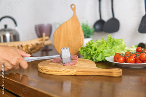 person beats meat with a meat tenderizer photo