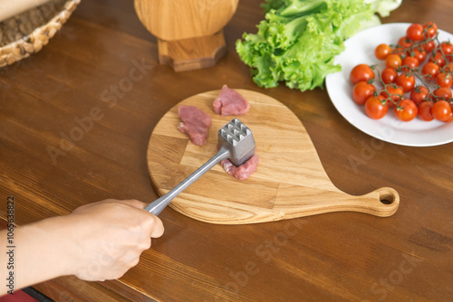 person beats meat with a meat pounder photo