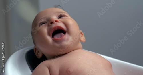 Baby laughing with mouth open during bath, smiling widely, joyful and happy, close-up moment in bath care. 800 fps slow-motion photo