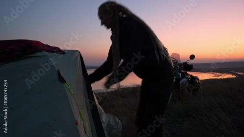 evening sunset at dusk motorcycle woman motorcyclist on solo moto trip camping leaving tent on background of mountain lake