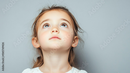 Young girl with long brown hair and blue eyes is smiling. She is wearing a white shirt and has a pink nose photo