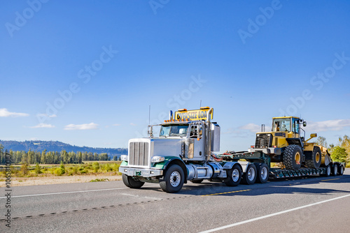 Fotografie Powerful white day cab big rig semi truck with oversize load sign on the roof tr
