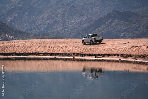 A 4x4 truck performs an off-road expedition on the shores of a mountain reservoir. photo