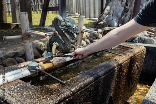 A tourist holds a ladle of water to wash his hands before going to the shrine in Japan