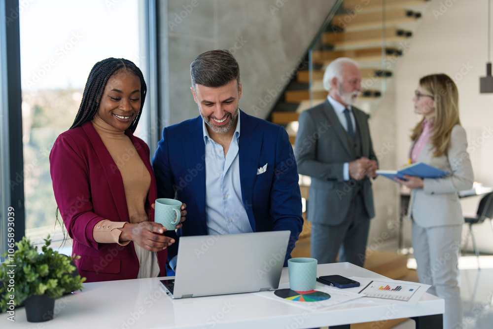 A diverse team collaborates with a focused businessman using a laptop, highlighting professional multitasking in a modern office setting. A diverse team collaborates with a focused businessman using a laptop, highlighting professional multitasking in a modern office setting.