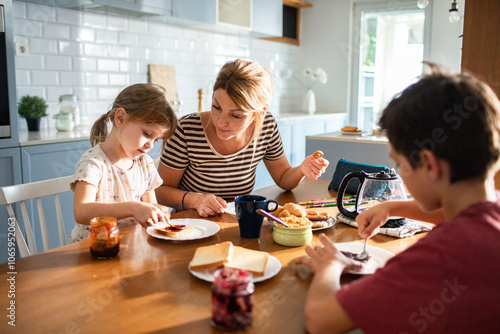 Mother and children enjoying breakfast together in kitchen photo