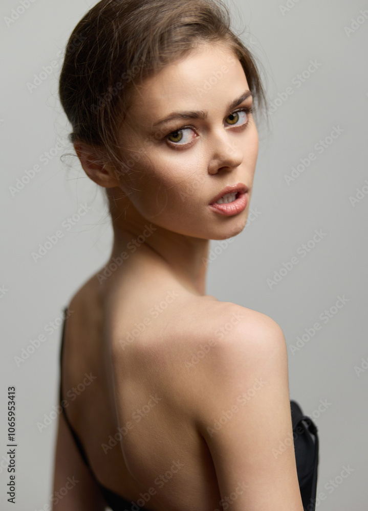 Portrait of a beautiful young woman with a soft expression, showcasing elegance in a black dress on a neutral gray background. Fashion and beauty concept. Portrait of a beautiful young woman with a soft expression, showcasing elegance in a black dress on a neutral gray background. Fashion and beauty concept.