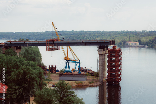 Concrete bridge over the river. Complex technical projects. A large architectural structure under construction. Temporary iron piles for the construction of columns. Large industrial equipment.