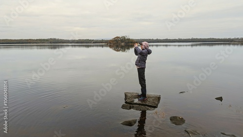 Obraz na płótnie Hiker girl standing on the rock reflected in lake at Coole park nature reserve, County Galway, Ireland, nature background w salonie