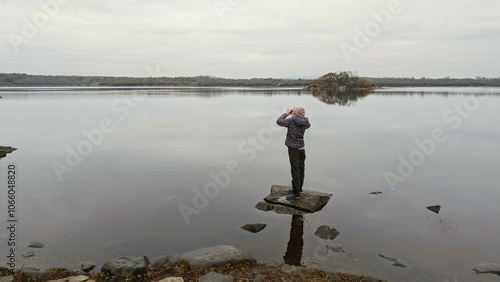 Obraz na płótnie Hiker girl standing on the rock reflected in lake at Coole park nature reserve, County Galway, Ireland w salonie