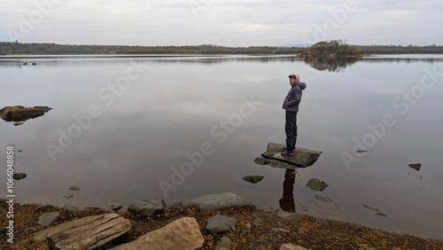 Obraz na płótnie Hiker girl standing on the rock reflected in lake at Coole park nature reserve, County Galway, Ireland, nature background w salonie