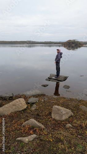 Obraz na płótnie Hiker girl standing on the rock reflected in lake at Coole park nature reserve, County Galway, Ireland, nature background w salonie