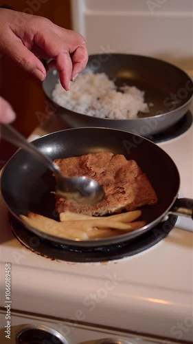 Woman cooking chicken Milanese, rice and French fries on old power stove, in old house in Latin America