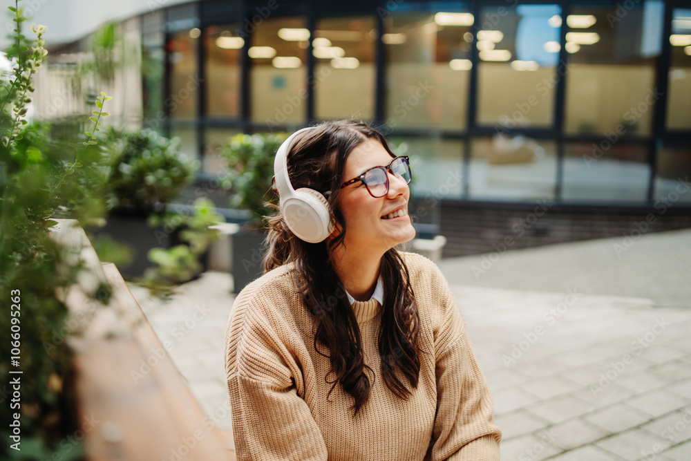 Fototapeta premium Young caucasian woman listening to music or audiobook outdoors 