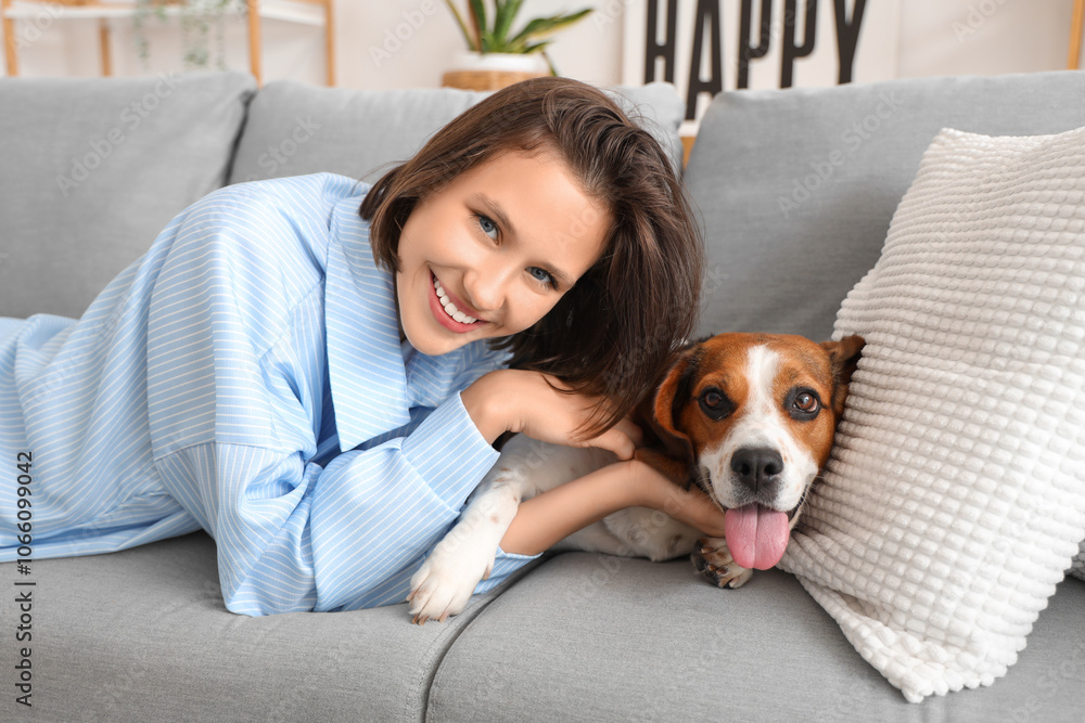 Young woman with cute Beagle dog lying on sofa at home Young woman with cute Beagle dog lying on sofa at home