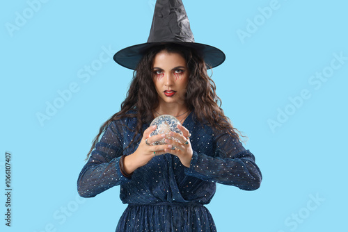 Young witch with crystal ball on blue background photo