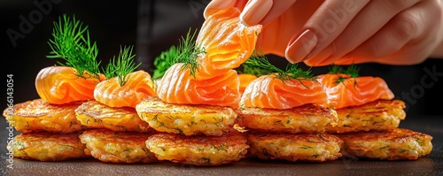 Hanukkah latkes flavor concept. A hand delicately adds a piece of salmon to a stack of crispy potato pancakes garnished with fresh dill showcasing delicious gourmet presentation photo