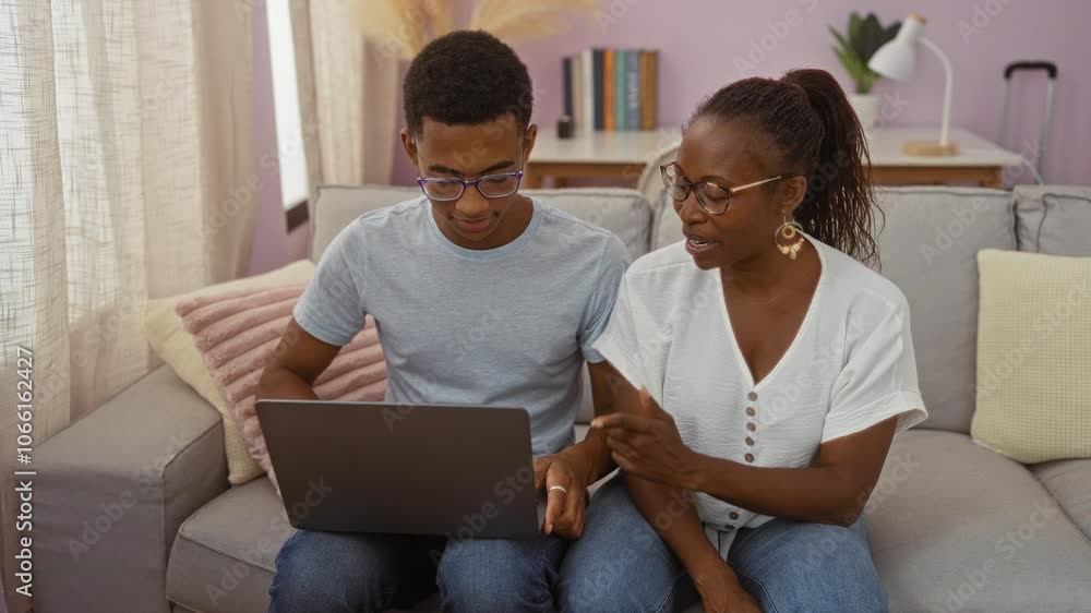 Mother and son using laptop together on couch in cozy living room, showing family bond and technology in a warm home setting. Mother and son using laptop together on couch in cozy living room, showing family bond and technology in a warm home setting.