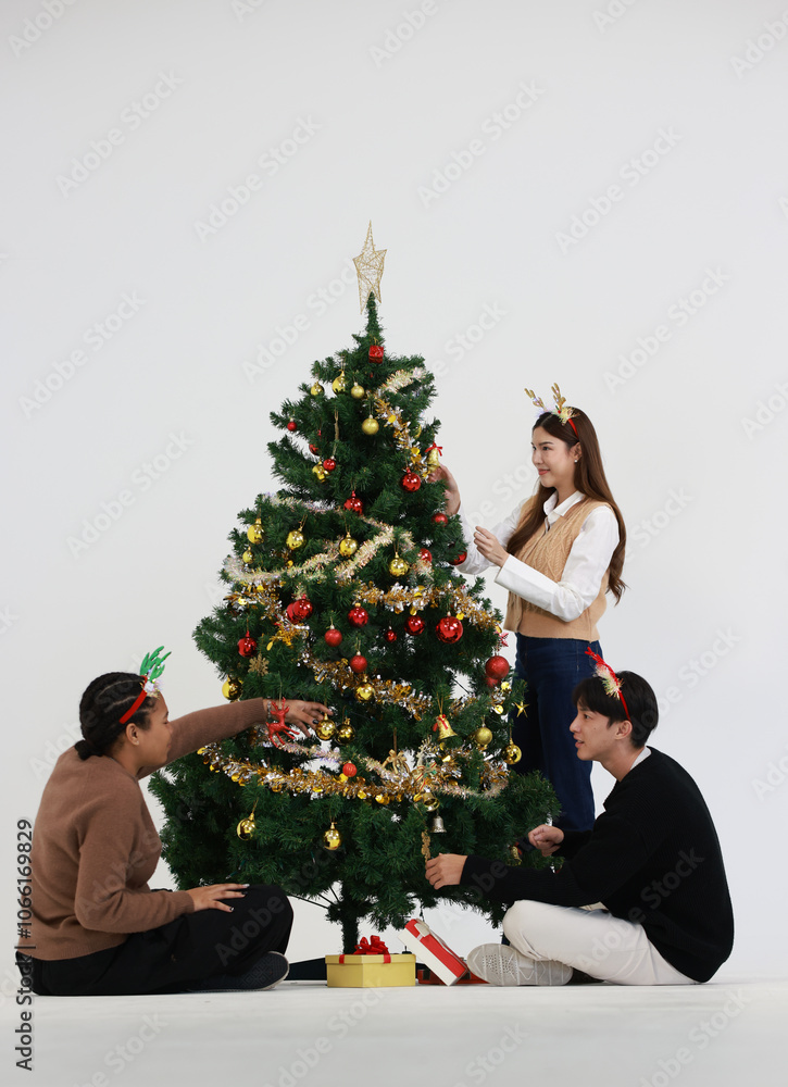 group of young diverse friends decorating the Christmas tree with presents and smiling in a festive holiday setting . Christmas celebration. group of young diverse friends decorating the Christmas tree with presents and smiling in a festive holiday setting . Christmas celebration.