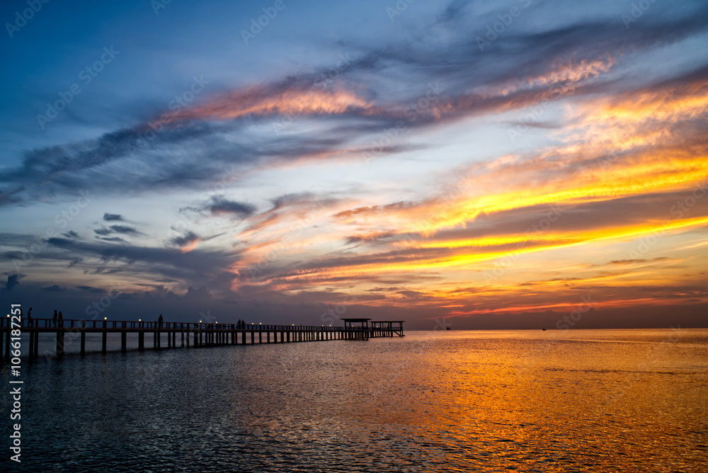 Naklejka premium landscape,The beautiful yellow sky in the evening after sunset reflects the sea and the bridge. 