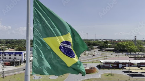 Drone slowly pans right from behind large Brazilian flag to overlooking a sambódromo next to Parque do Meio do Mundo in Macapá, Amapá, Brazil photo