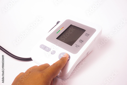 A man is pressing the start button on a digital blood pressure monitor.