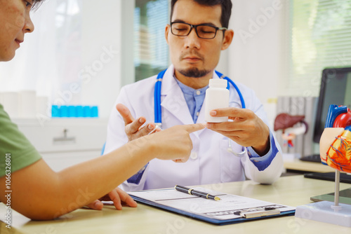 A doctor man sits at a desk in a hospital, explaining heart disease symptoms to a female patient. They discuss chest pain, palpitations, fatigue, dizziness, and the risks of myocardial ischemia photo