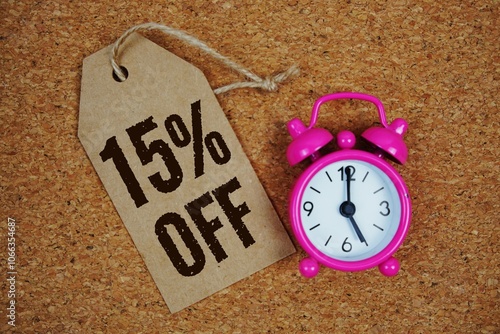 Sale 15% Off text on price tag with alarm clock on cork board background photo