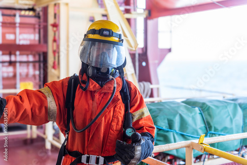 A firefighter in full protective gear, mask, and oxygen tank stands ready during a fire drill on board. Fully equipped, he executes fire suppression tasks with required precision. photo