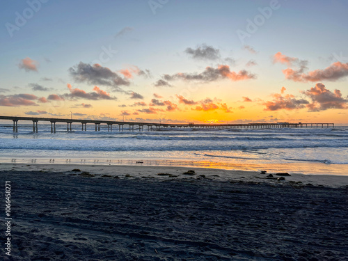 Sunset behind ocean beach pier with crashing waves