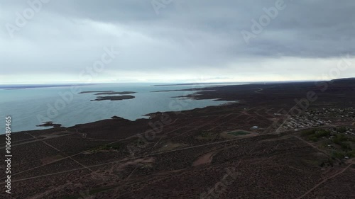 Wide aerial view of the Embalse Ezequiel Ramos Mexía and the city of Picún Leufú nearby, cloudy, copy space, pedestal shot photo