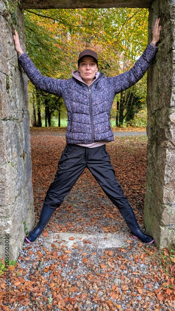 Portrait of pretty hiker girl at medieval stone entrance at Coole park nature reserve at county Galway, Ireland, people background