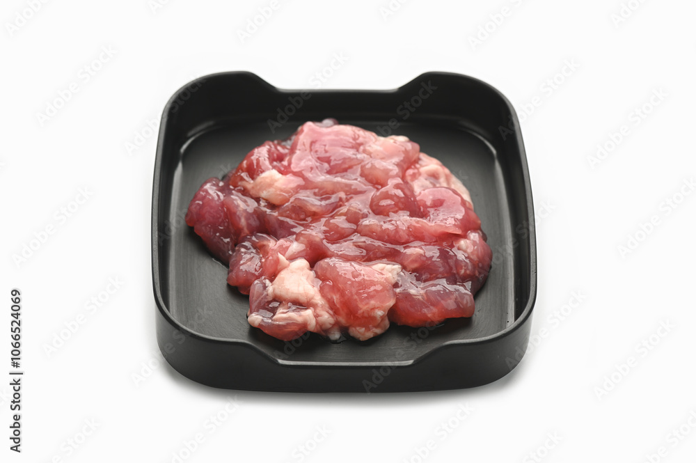 Marinated tender pork in black tray on white background.
Marinated tender pork in black tray on white background.