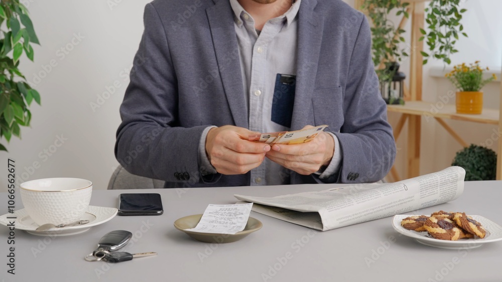 Man sitting at table at cafe restaurant and reading newspaper, paying bill with cash euro banknotes. Commercial business payments. Man sitting at table at cafe restaurant and reading newspaper, paying bill with cash euro banknotes. Commercial business payments.