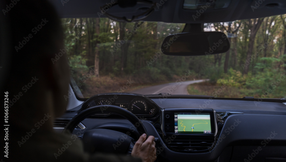 Woman driving a car on a forest road, shot from behind