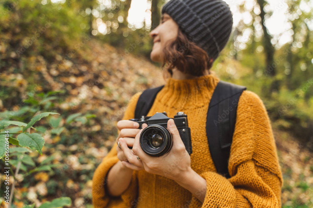 Young Caucasian woman photographer with analog photo camera enjoying autumn nature and weather