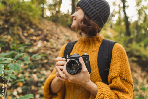 Young Caucasian woman photographer with analog photo camera enjoying autumn nature and weather