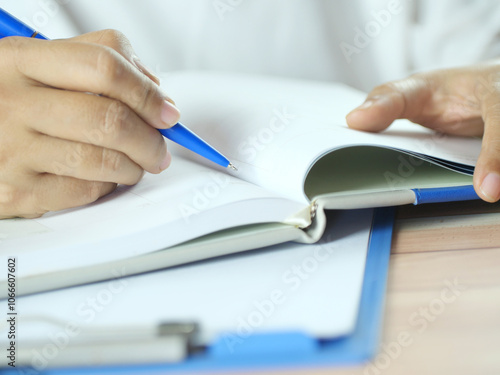 Hand holding pen writing on note paper. Finance business concept. Copy space.