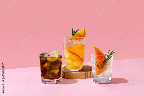 Cocktails with ice on a pink background. Set with different types of cocktails on a pink table. Whiskey with cola, Cuba Libre, gin and tonic with grapefruit and orange fresh.