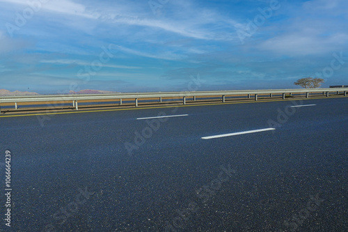 An empty road leading into Dubai’s majestic skyline, framed by towering skyscrapers against the clear sky