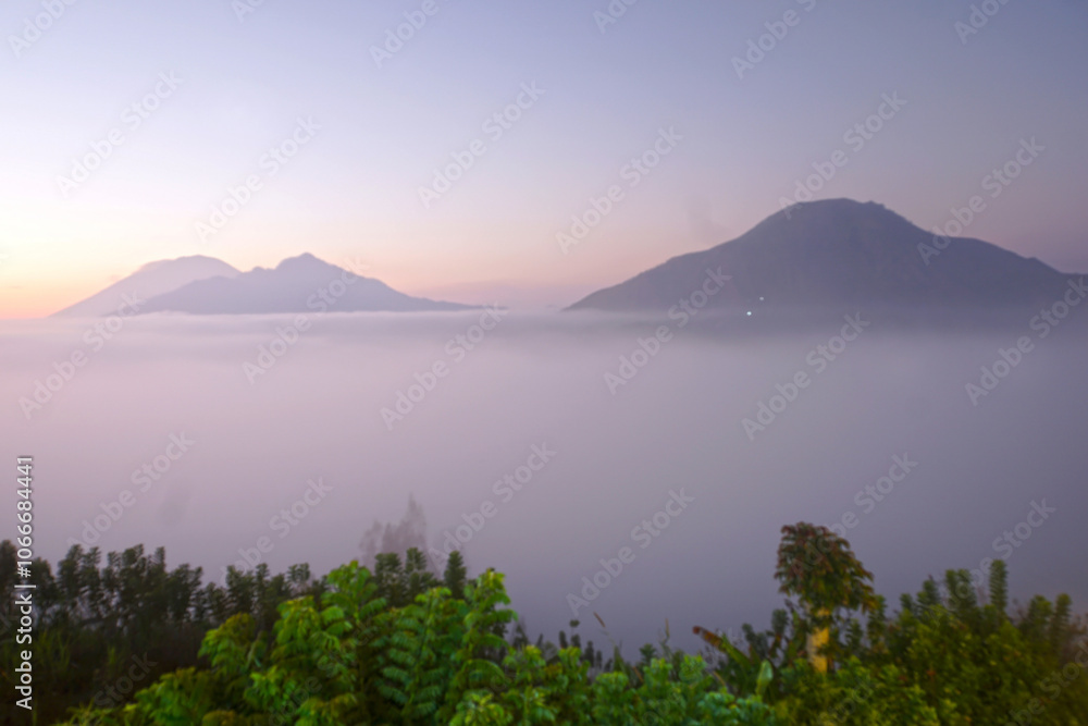 Blur natural nature landscape background of the sunrise view with fog and warm sunlight over mountains. Desa Pinggan, Kintaman, Bali, Indonesia. Blur natural nature landscape background of the sunrise view with fog and warm sunlight over mountains. Desa Pinggan, Kintaman, Bali, Indonesia.