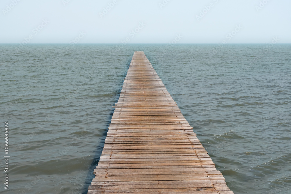 A wooden pier extends into calm waters, creating a serene and inviting atmosphere, perfect for contemplation and relaxation. A wooden pier extends into calm waters, creating a serene and inviting atmosphere, perfect for contemplation and relaxation.
