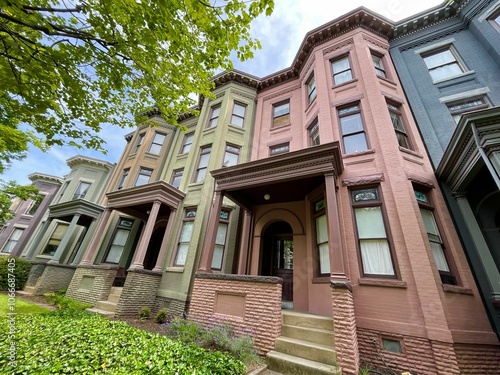 Row of colorful vintage houses with lush greenery and blue sky. Richmond, Virginia