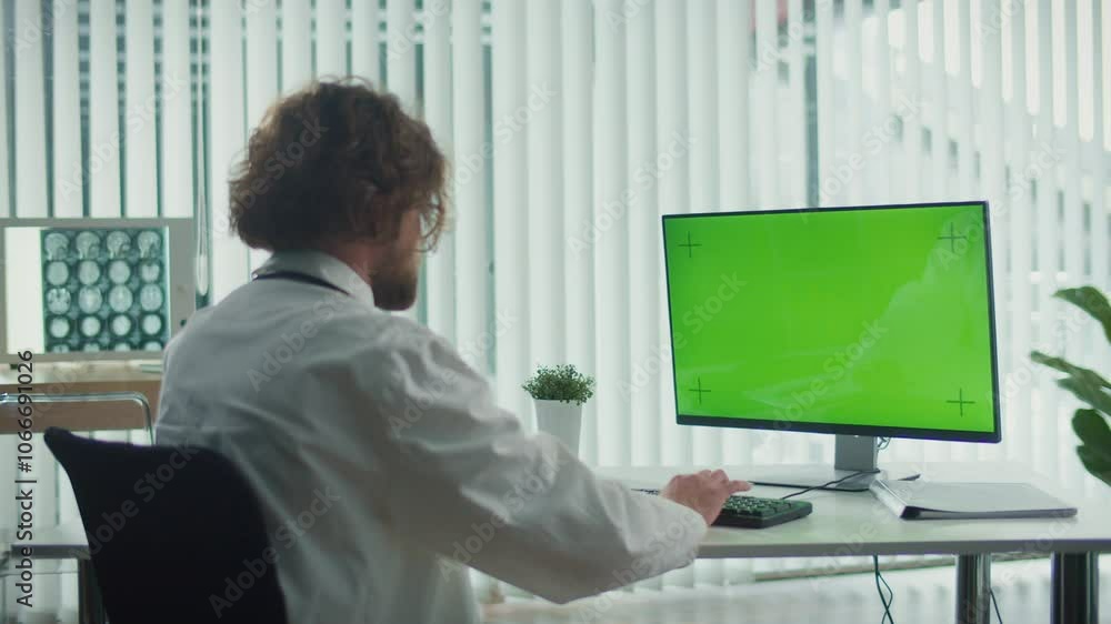 A Doctor Sits in His Modern Office, Working on a Computer with a Green Screen. He Delivers Medical Services to Patients, Tailored to the Needs of Urban Dwellers. Healthcare in Urban Environments. A Doctor Sits in His Modern Office, Working on a Computer with a Green Screen. He Delivers Medical Services to Patients, Tailored to the Needs of Urban Dwellers. Healthcare in Urban Environments.