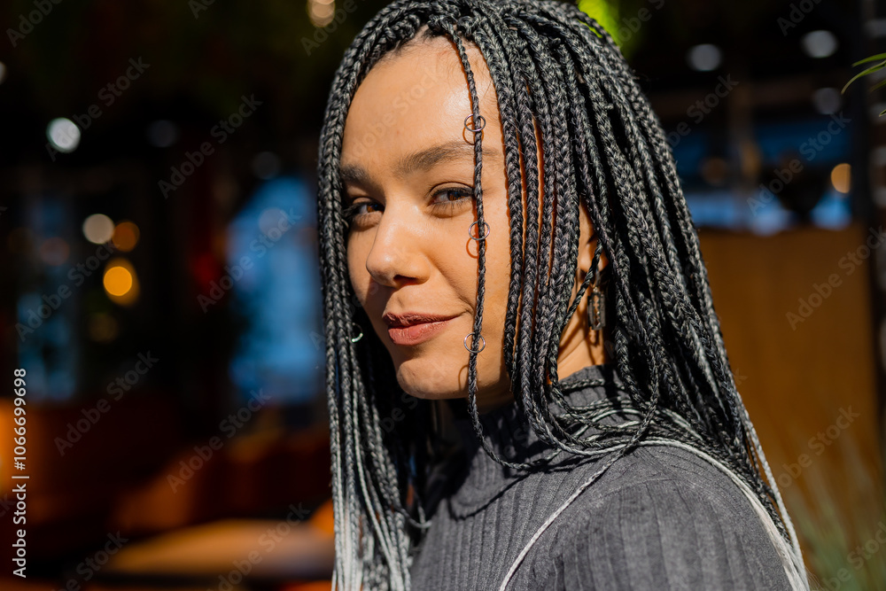 young woman with afro braids is sitting in a coffee shop and drinking a cocktail young woman with afro braids is sitting in a coffee shop and drinking a cocktail