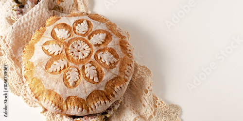 Top view of fresh bread with a floral pattern on a white table